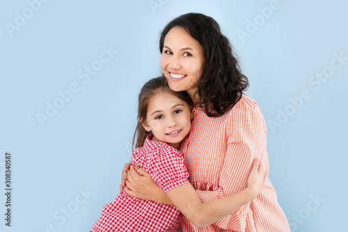 Happy little girl and her mother on color background