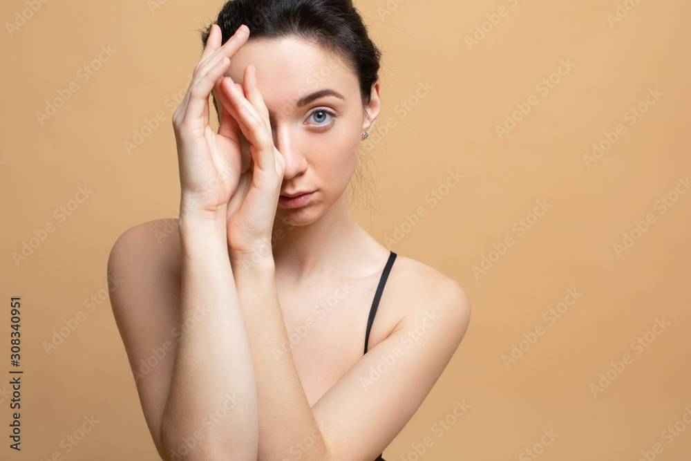 Image with beautiful brunette touching her lips on grey background. The concept of beauty and skin care Image with beautiful brunette touching her lips on grey background. The concept of beauty and skin care
