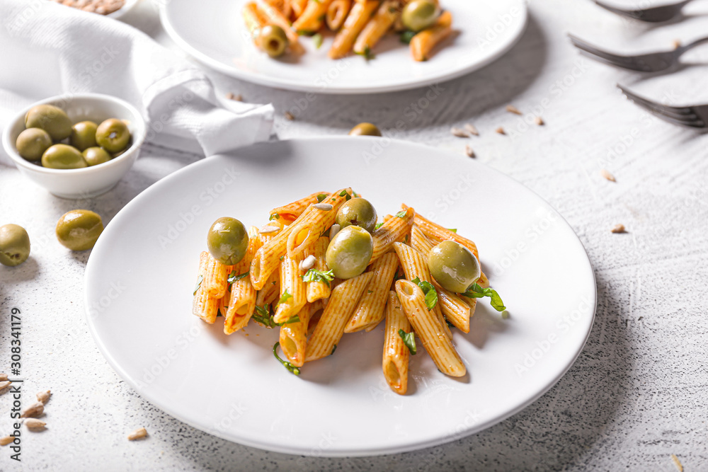 Plate with tasty pasta and olives on white table Plate with tasty pasta and olives on white table