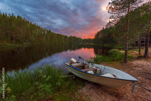Evening Fishing In the border of Ala-Juumajarvi lake in Oulanka National Park, the sky in sunset colors is at background. Ostrobothnia, Finland. photo