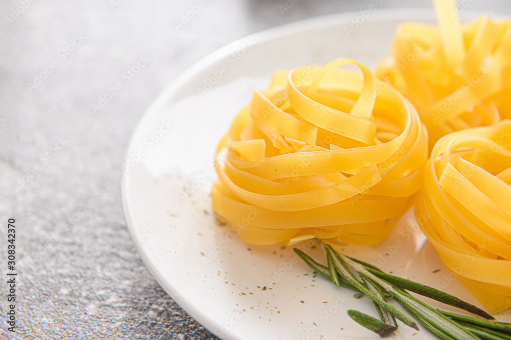 Plate with uncooked pasta on table, closeup