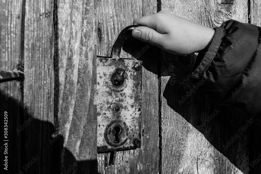 Child trying to open old wooden door. Rustic door handle Child trying to open old wooden door. Rustic door handle