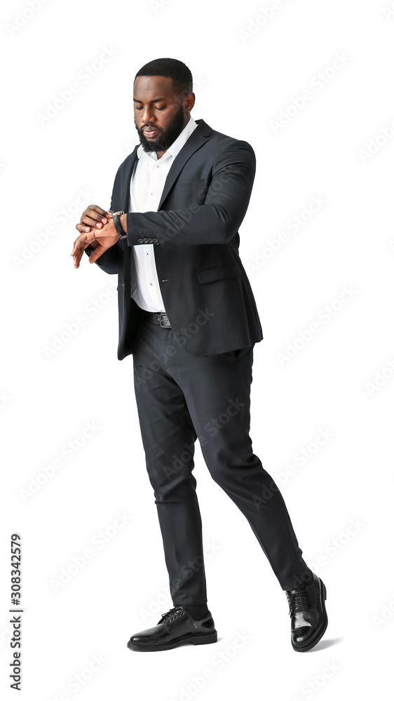 Stylish African-American man looking on his wrist watch against white background Stylish African-American man looking on his wrist watch against white background