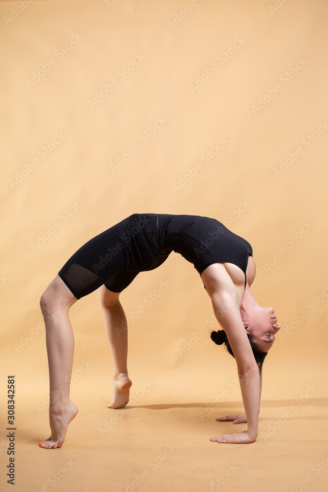 Naklejka premium Side view portrait of beautiful young woman wearing white tank top working out against orange background, doing stretching.