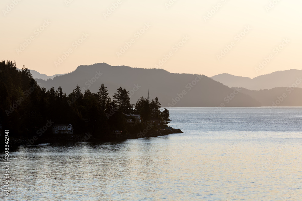Sun raising over Ketchikan Alaska soft tree lined mountains in the background calm water in the foreground 