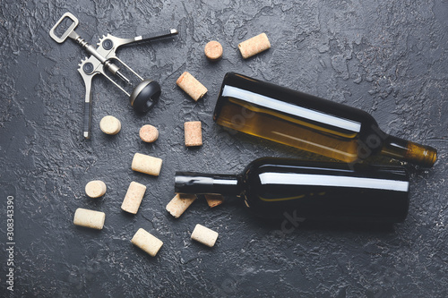 Bottles of wine with corks and opener on dark background