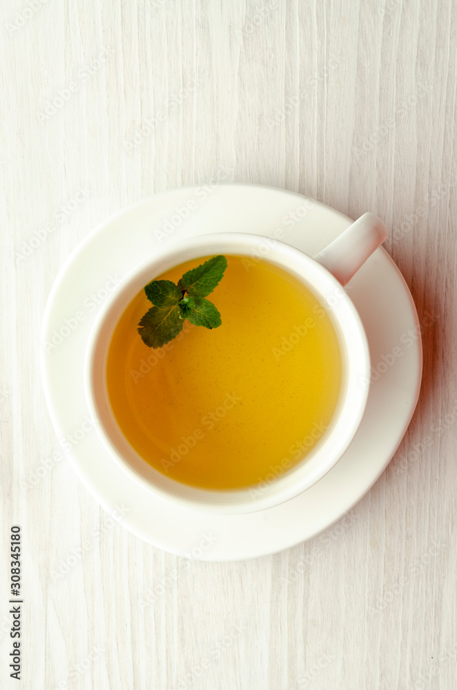 Cup and teapot of herbal tea with fresh mint on wooden Cup and teapot of herbal tea with fresh mint on wooden