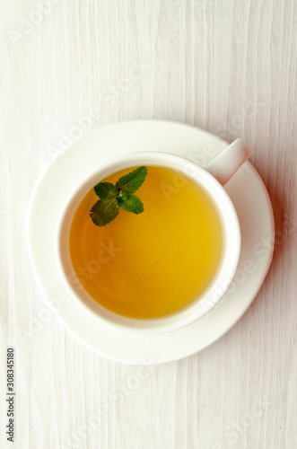 Cup and teapot of herbal tea with fresh mint on wooden