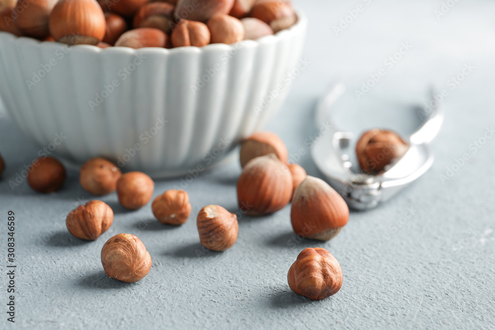 Bowl with tasty hazelnuts and cracker on color background Bowl with tasty hazelnuts and cracker on color background