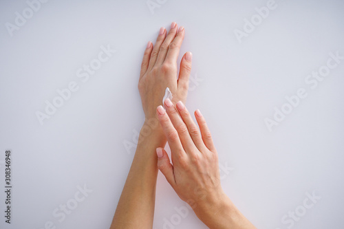 Female hands with cream and a beautiful manicure on a gray background. Spa treatment.