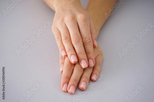 Female hands with a beautiful manicure on a gray background.