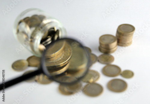 Rising coins, magnifying glass, Pile of mixed iron money coins background