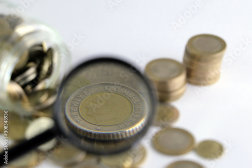 Rising coins, magnifying glass, Pile of mixed iron money coins background