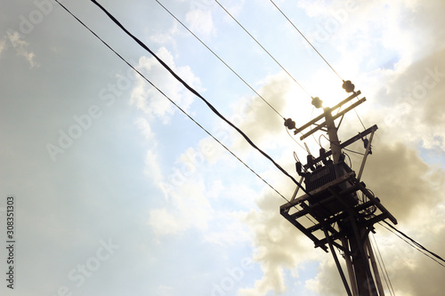 Utility pole supporting overhead power line cables against blue sky as copy space