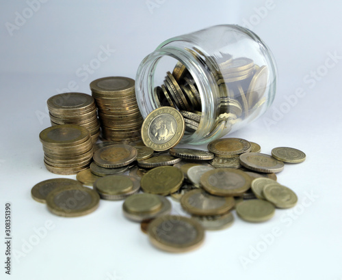 Rising coins, magnifying glass, Pile of mixed iron money coins background