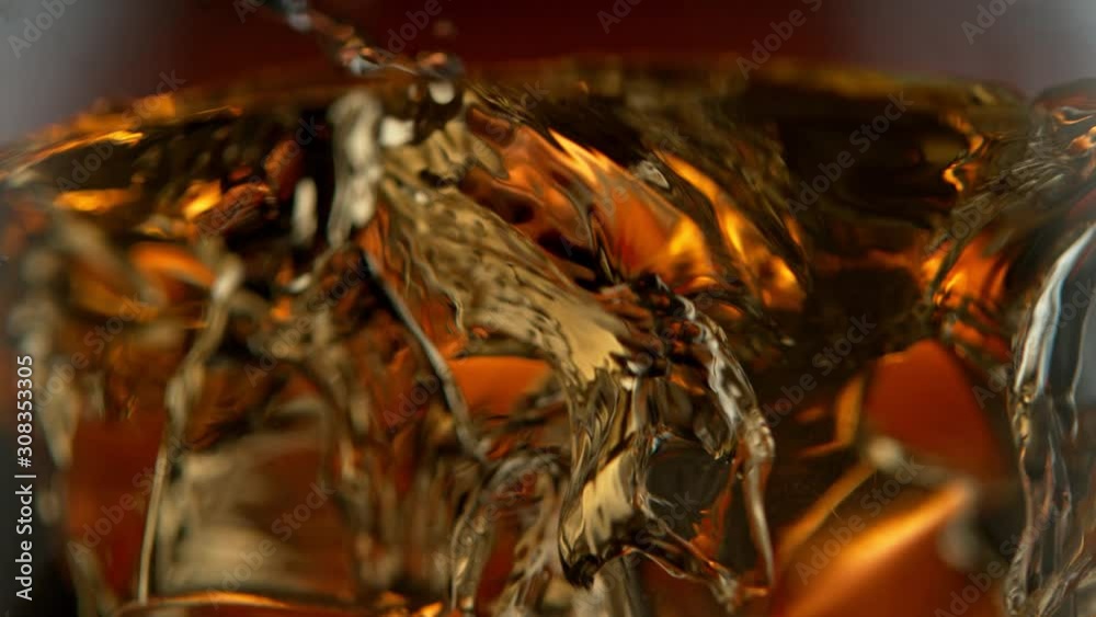 Super Slow Motion Detail Shot of Ice Drop into Glass with Whiskey at 1000fps. Super Slow Motion Detail Shot of Ice Drop into Glass with Whiskey at 1000fps.