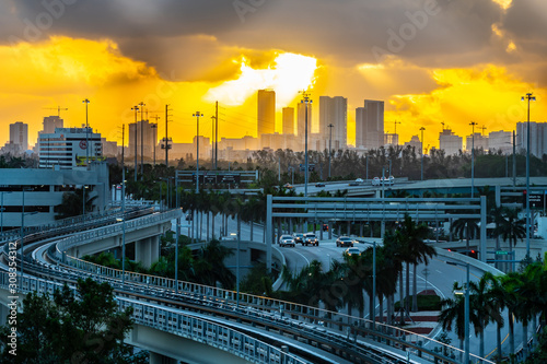 Stunning city skyline morning sunrise in background, cars commuting on the highway, and an empty section of the Miami International Airport (MIA) train line. photo
