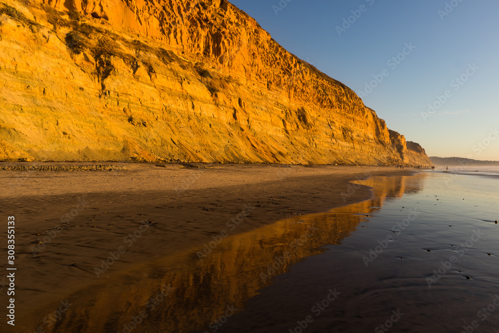 A sandstone bluff at sunset with a reflection on the beach at low tide, at the Torrey Pines State Natural Reserve in La Jolla, California, located in San Diego County.