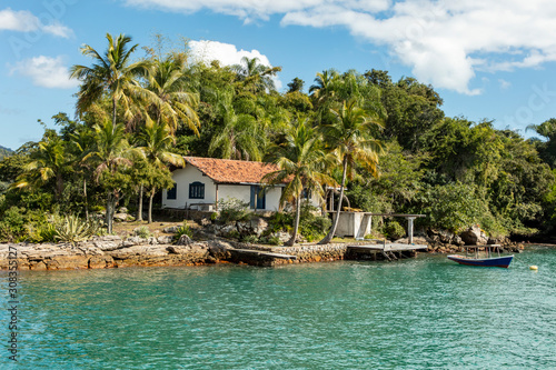 Boats and house in beach big island (Ilha Grande), sea of Angra dos Reis bay with beautiful large mountains in the background, beach holidays on the coast of Rio de Janeiro, Brazil