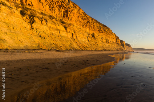 Фотография A sandstone bluff at sunset with a reflection on the beach at low tide, at the Torrey Pines State Natural Reserve in La Jolla, California, located in San Diego County