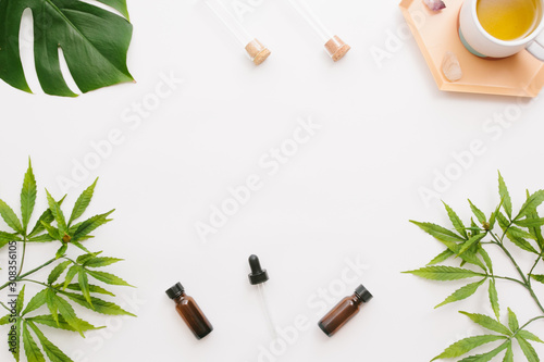 Glass bottles with CBD oil, THC tincture and hemp leaves on a white background. Flat lay, minimalism. Cosmetics CBD oil.