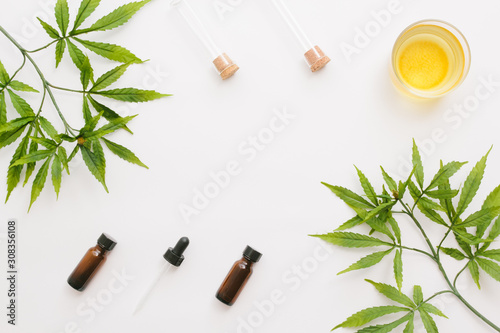 Glass bottles with CBD oil, THC tincture and hemp leaves on a white background. Flat lay, minimalism. Cosmetics CBD oil.