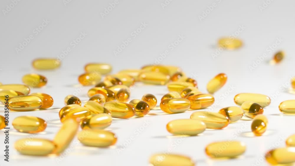 Vitamins and supplements fall onto a white surface in slow motion