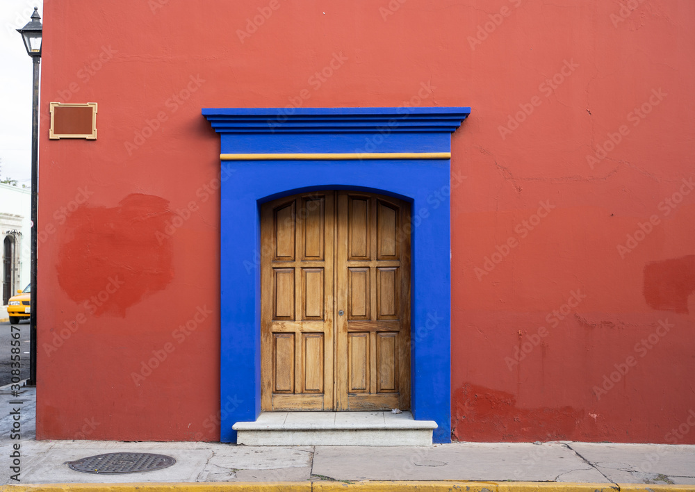 red and blue old house facade with wooden door