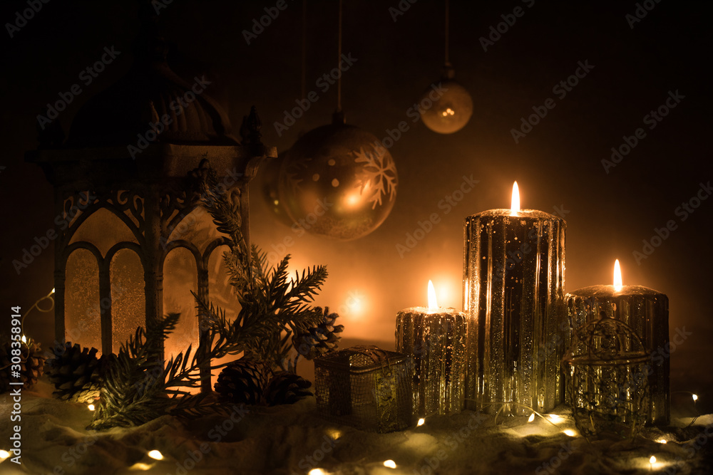 Creative artwork decoration. Christmas decoration with burning candles on a dark background. Christmas ornaments over dark golden background with lights.