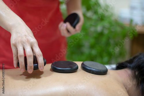 Woman putting zen balast stones on back, massage relaxing