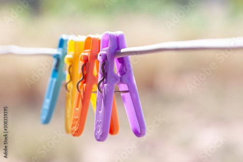 Fotografie Multi colored plastic clothes clips on the wire on blur nature background