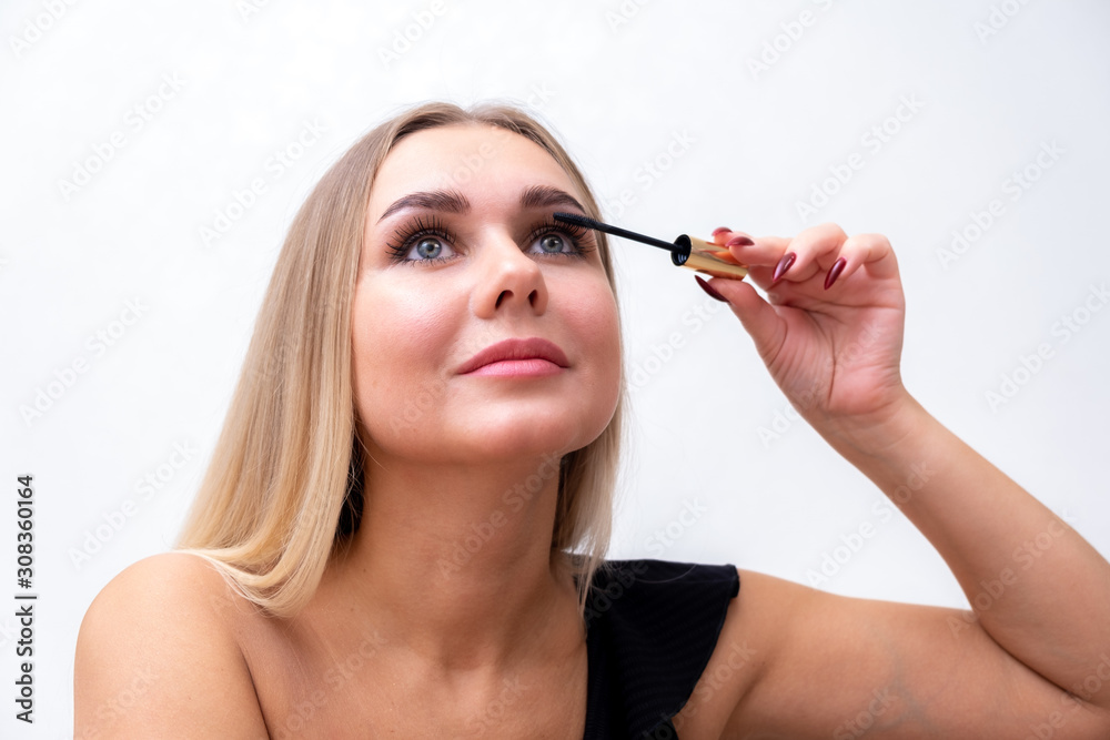 Headshot of female with bright makeup applying mascara on eyelashes. Headshot of female with bright makeup applying mascara on eyelashes.