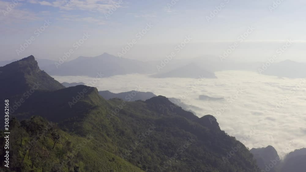 Aerial view Drone flying over a beautiful green mountain forest. Tourist destination on a hilltop during the foggy and beautiful light in the morning and sunset in Chiang Rai Thailand. Footage B roll. Aerial view Drone flying over a beautiful green mountain forest. Tourist destination on a hilltop during the foggy and beautiful light in the morning and sunset in Chiang Rai Thailand. Footage B roll.