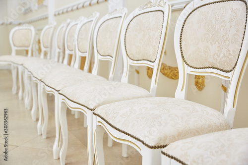 A row of white chairs of classic design in a bright room.