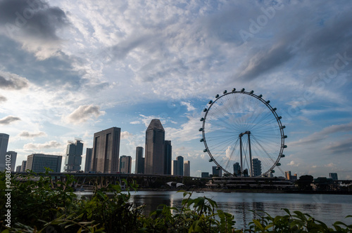 Singapore flyer on a cloudy day with towering buildings in the backdrop