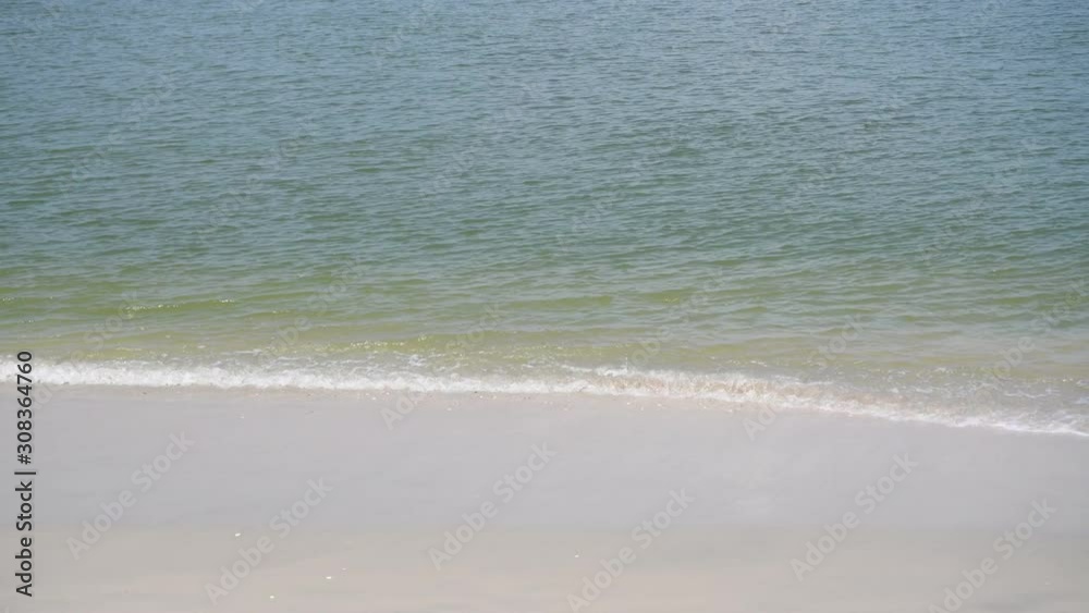 The sea with waves hit the sandy beach in the morning