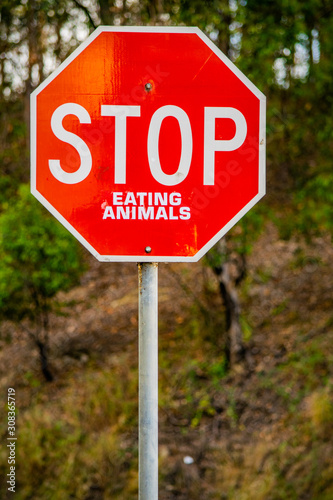 Vertical image of a tradional red traffic warning sign with humorous sustainable message 'STOP Eating Animals' in support of vegetarian and vegan lifestyle