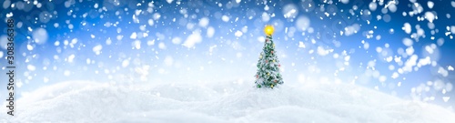 Wintery landscape background with single Christmas tree on glistening white snow drifts surrounded by snowfall