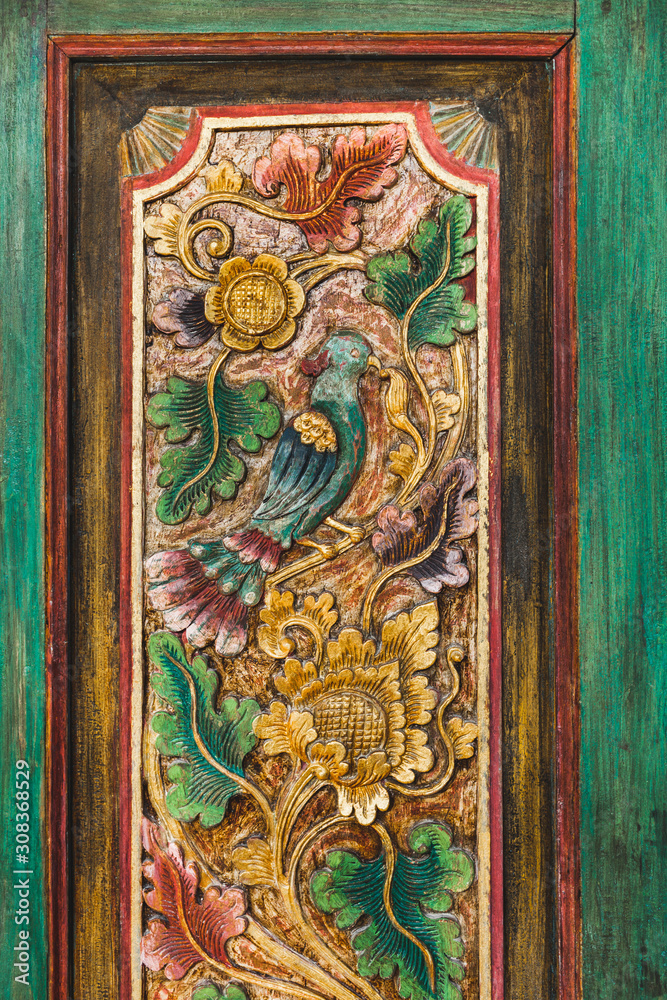 Close-up details of traditional balinese handmade carved wooden door. Bali style furniture with flowers ornament. Beautiful local tradition. 