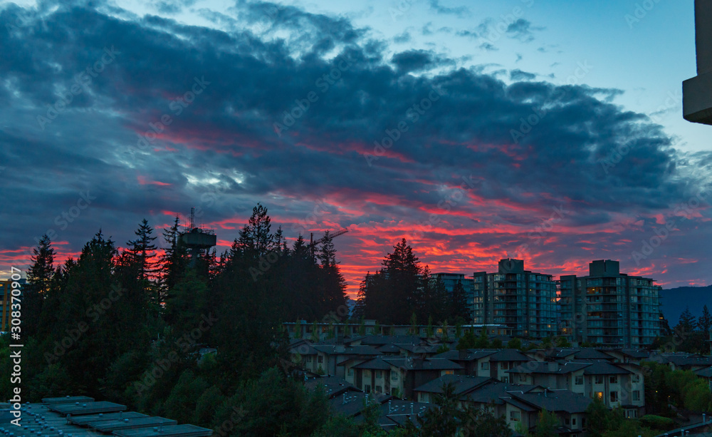 Fototapeta premium Flamboyant sunset over North Shore mountains overlooking UniverCity on Burnaby Mountain
