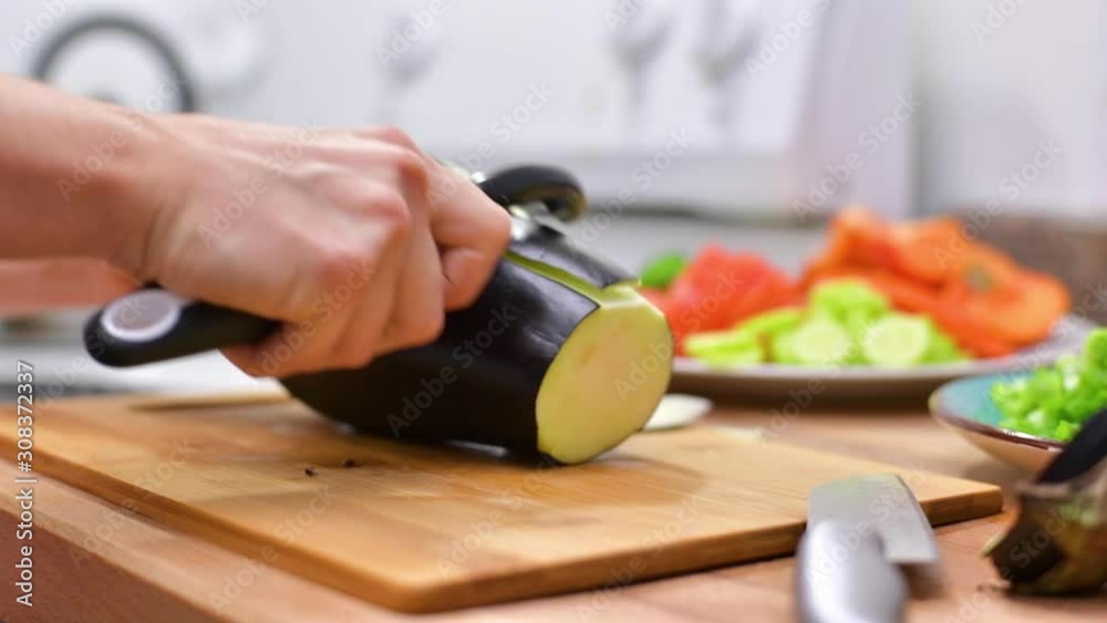 Woman using kitchen knife slicing fresh eggplant on wooden board Woman using kitchen knife slicing fresh eggplant on wooden board