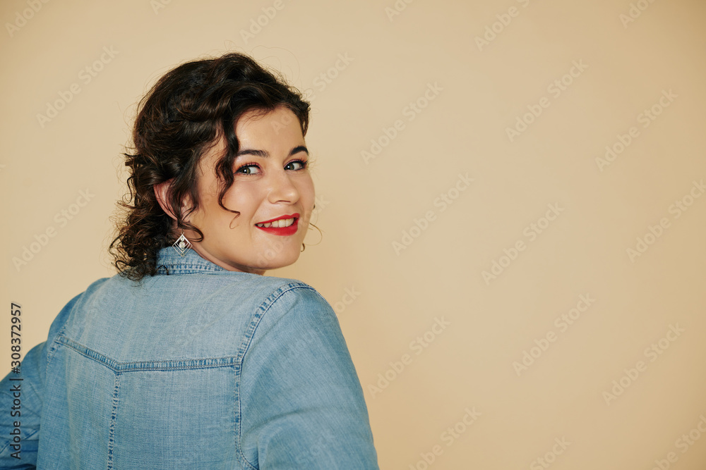 Portrait of young beautiful woman in denim shirt turning back and smiling at camera Portrait of young beautiful woman in denim shirt turning back and smiling at camera