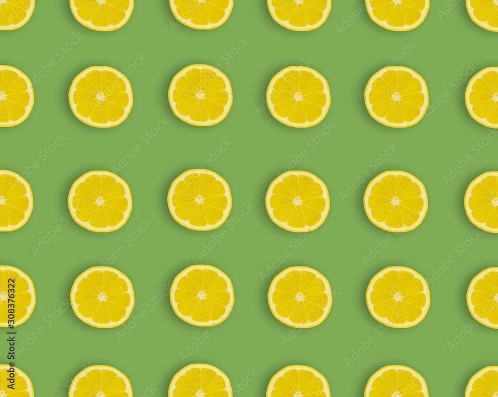 Pattern.Fresh lemon slices on a green background.Flat lay, top view - image background.