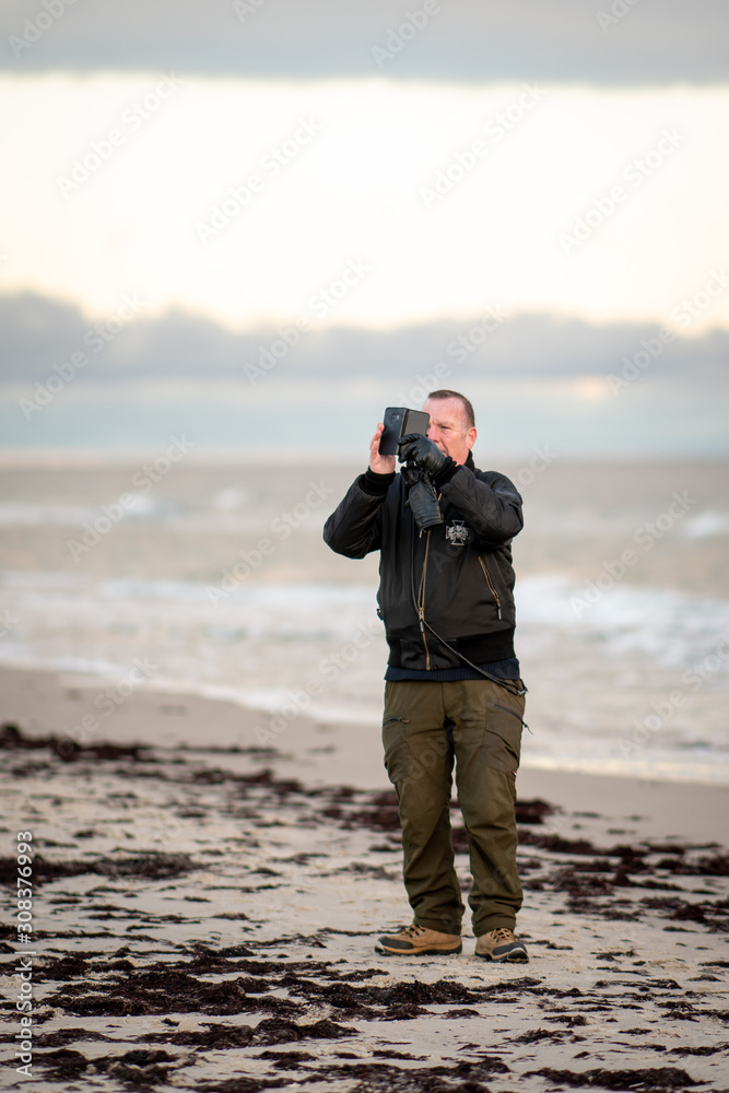 Obraz premium man at the beach taking photo with camera