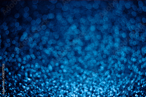 Festive blurry blue background of sequins with side effect.