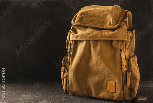 Obraz na płótnie Hipster yellow backpack on table on dark background copy space