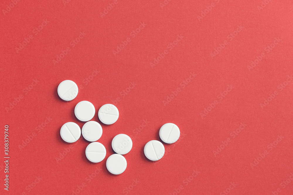 Round pills scattered on a red background. Top view, copy space. Pharmacy concept Round pills scattered on a red background. Top view, copy space. Pharmacy concept