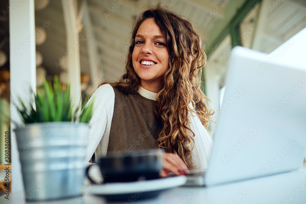 Attractive young curly brunette looking at camera and smiling in café Attractive young curly brunette looking at camera and smiling in café