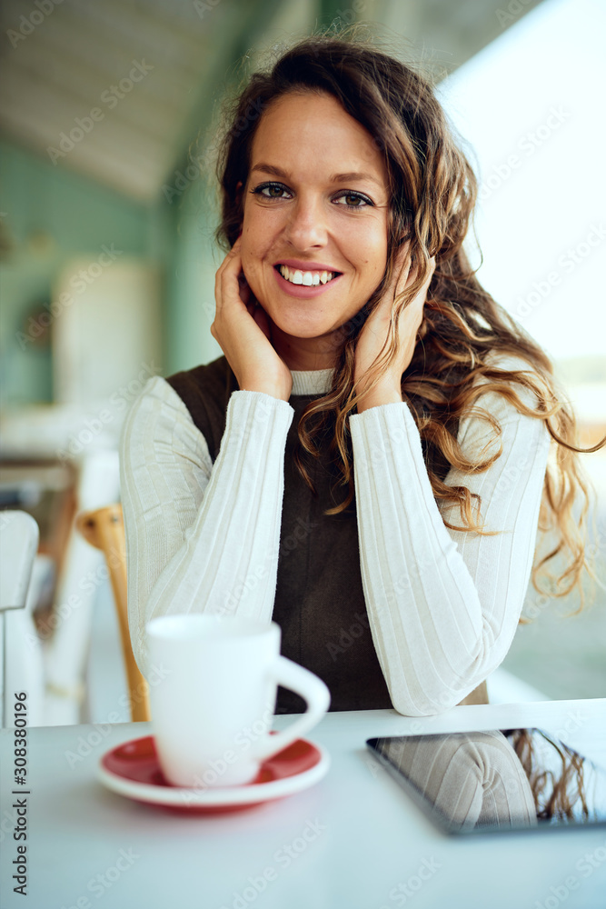 Attractive curly woman holding hot tea cup in café Attractive curly woman holding hot tea cup in café