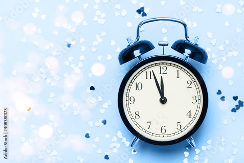 Alarm clock on a blue background with small hearts. The concept of the time of love, the time of date, the wedding, the day of St. Valentine, New Year